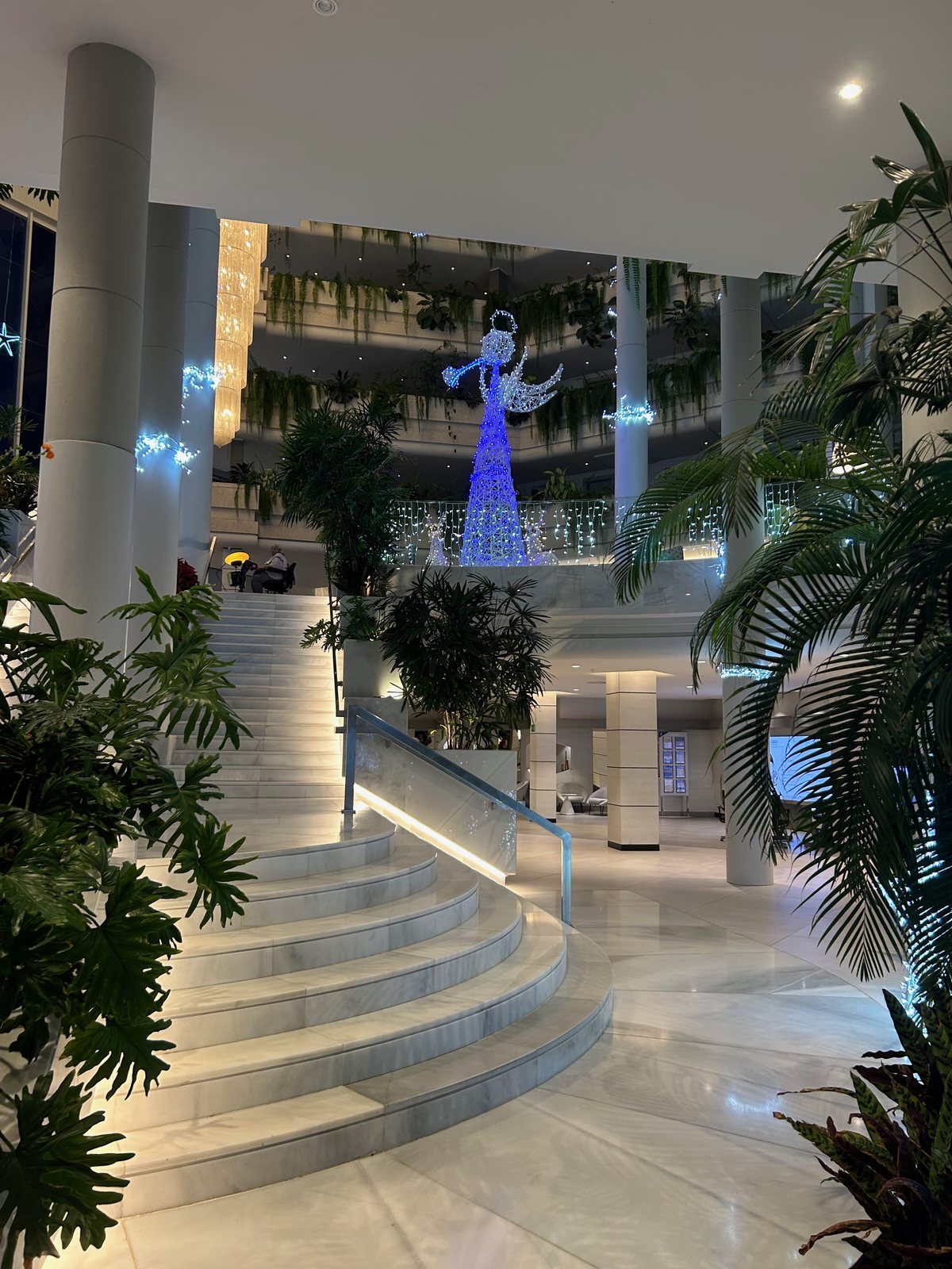 The sweeping staircase, greenery and Christmas lights in the hotel foyer
