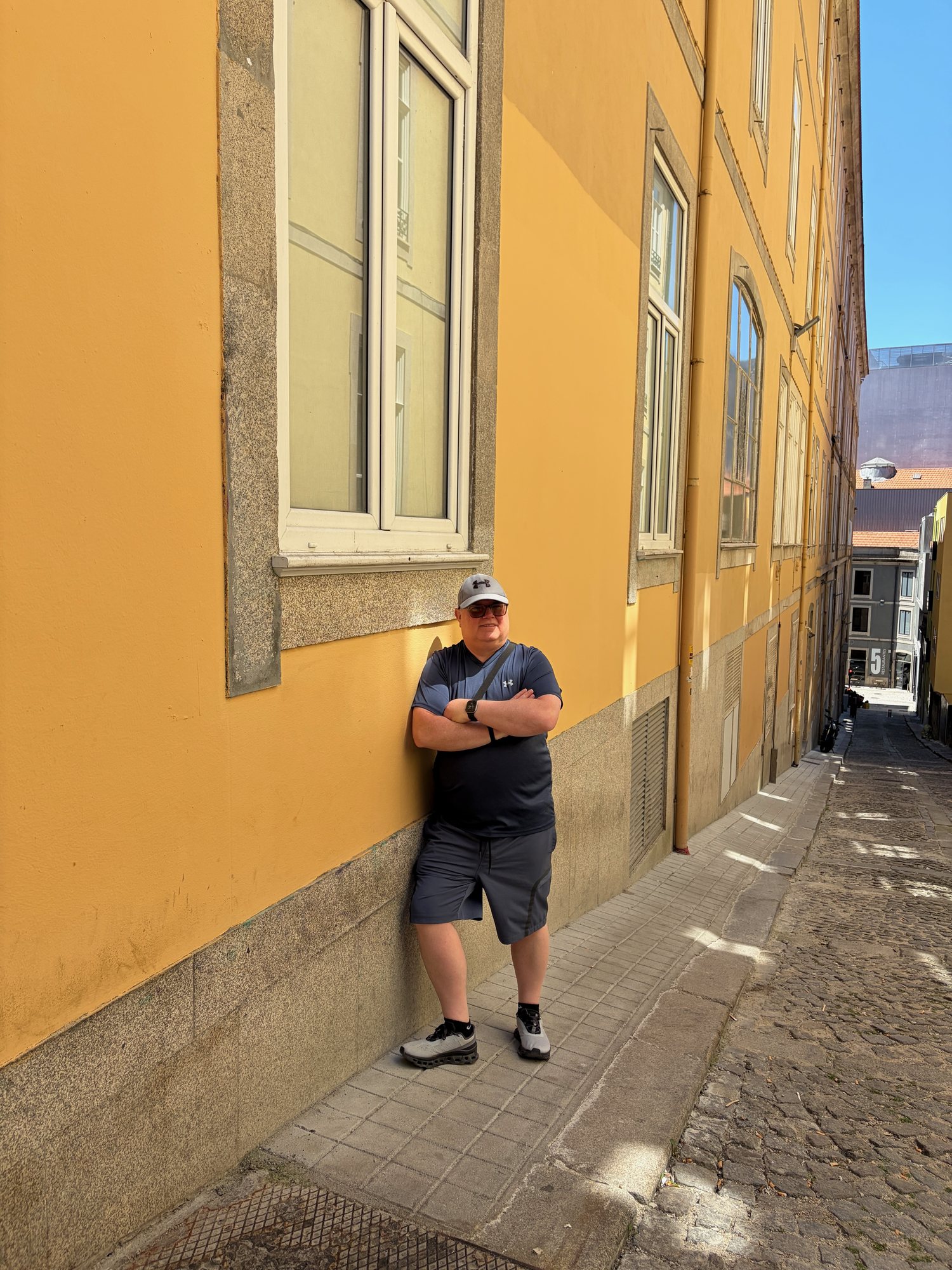 Chris beside a yellow building on a steep street near Bolhão in Porto
